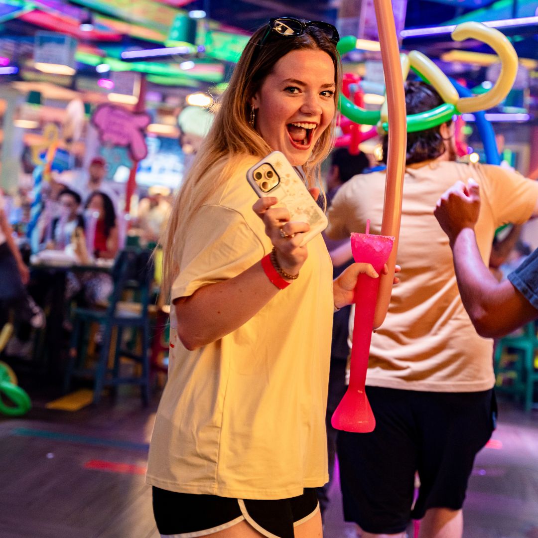 Guest smiling with a frozen pink yard drink on the dance floor at Señor Frog’s Playa del Carmen